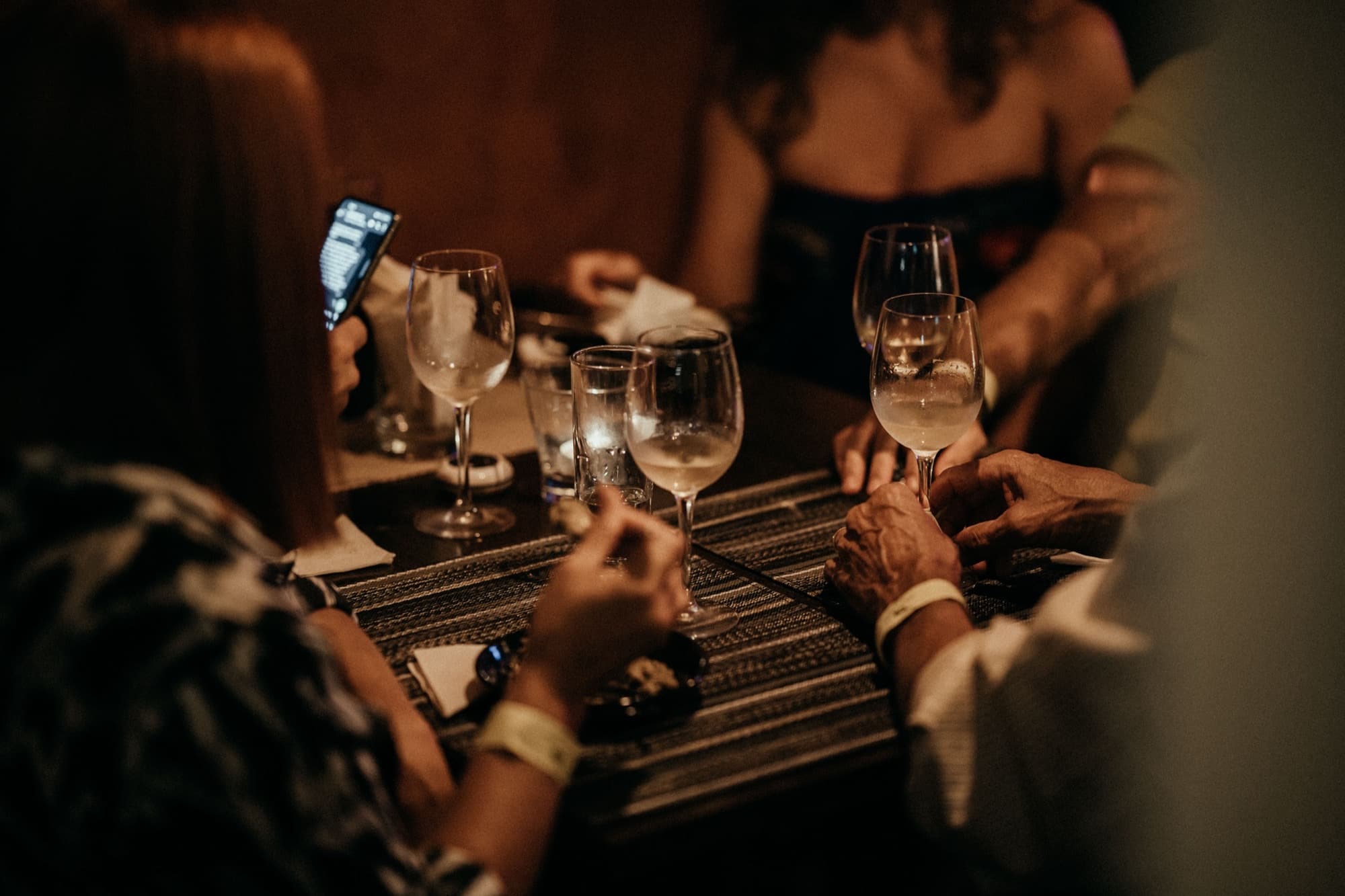 Wine glasses and hands around a table at an evening event