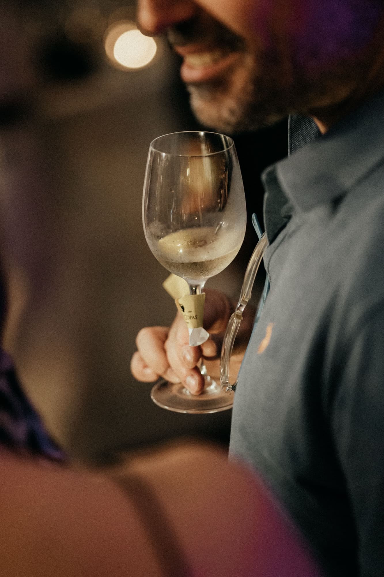 A guest smiling over a glass of white wine